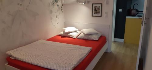 a small room with a red bed with two pillows at Apartament MONDRIAN in Płock