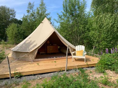 a tent with a chair on a wooden deck at Fristad Glamping Tent Vitsand in Gunsjögården