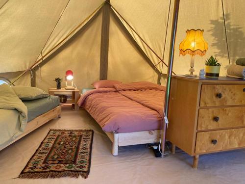 Fristad Glamping Tent Vitsand في Gunsjögården: غرفة نوم بسرير في خيمة