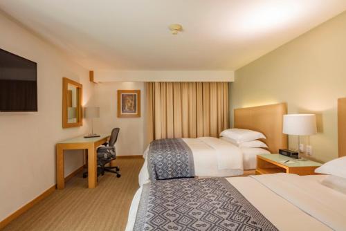 a hotel room with two beds and a desk at Presidente InterContinental Puebla by IHG in Puebla