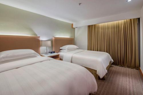 a hotel room with two beds and a window at Presidente InterContinental Puebla by IHG in Puebla