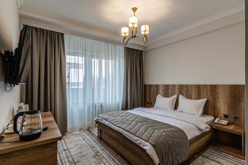 a bedroom with a large bed and a chandelier at Oscar Hotel by AG Hotels Group in Almaty