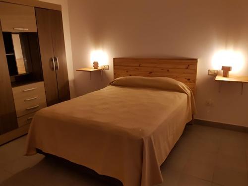 1 dormitorio con 1 cama y 2 luces en la pared en Residencial Las Lechuzas en 