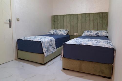 two twin beds in a room with marble floors at A&R Apartment Nador Jadid Hay Al Matar ,Klimatisiert,Air-Conditioned in Nador