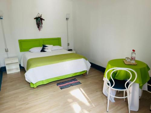 a bedroom with a large bed and a green table at ICCE HOTEL in Santiago