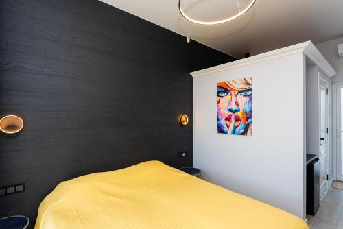 a bedroom with a yellow bed and a painting on the wall at 2NIGHT in Šventoji in Palanga