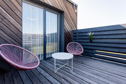 two pink chairs and a table on a deck at 2NIGHT in Šventoji in Palanga