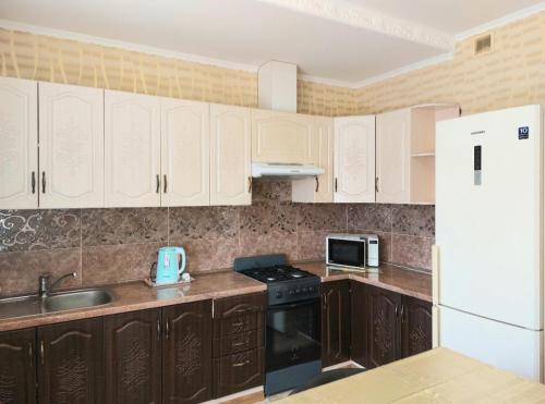 a kitchen with wooden cabinets and a white refrigerator at Апартаменты, 2 комн. 6 мест in Kropyvnytskyi