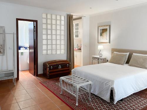 a bedroom with a white bed and a suitcase at Casa do Pelourinho in Belmonte