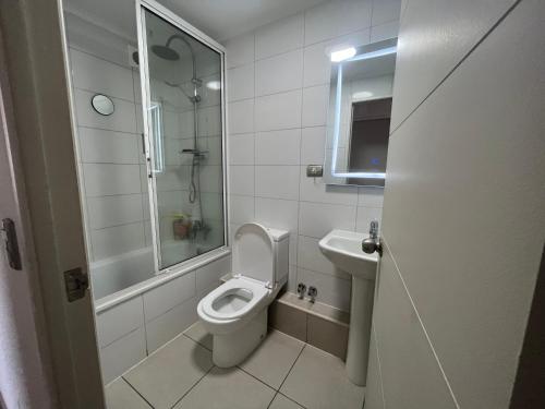 a white bathroom with a toilet and a sink at Departamento full equipamiento in San Pedro de la Paz
