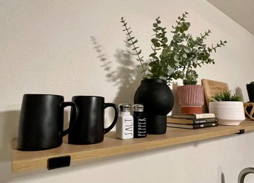 a shelf with two black coffee mugs and a vase at Cozy Adventure Casita in St. George