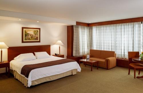 a hotel room with a bed and a chair at Torre de Cali Plaza Hotel in Cali