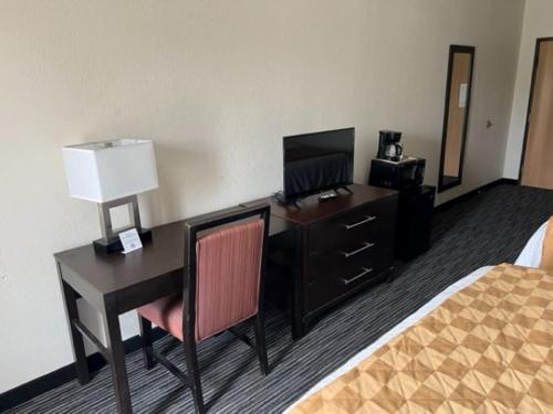 a hotel room with a desk and a bed at American Inn and Suites Houghton Lake in Houghton Lake