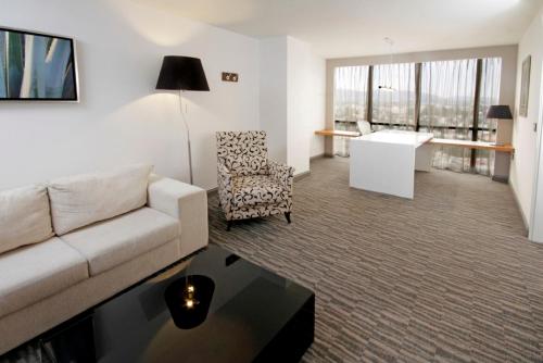 a living room with a couch and a table and a desk at Presidente InterContinental Guadalajara by IHG in Guadalajara