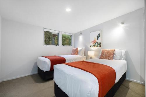 two beds in a room with white walls and windows at Bluebird Stay in Queenstown
