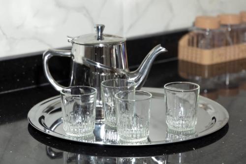 a tray with four glasses and a tea kettle at A&R Apartment Nador Jadid Hay Al Matar ,Klimatisiert,Air-Conditioned in Nador