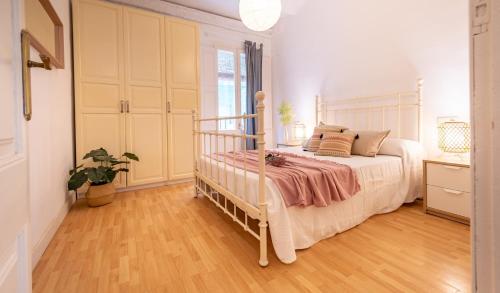 Schlafzimmer mit einem weißen Bett und Holzboden in der Unterkunft Acogedor apartamento en Serrallo in Tarragona