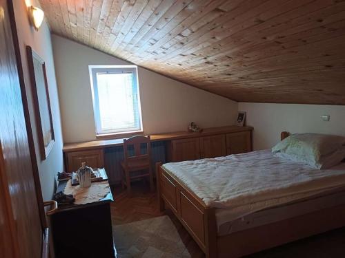 Schlafzimmer mit einem Bett, einem Schreibtisch und einem Fenster in der Unterkunft Apartman u potkrovlju in Sremski Karlovci