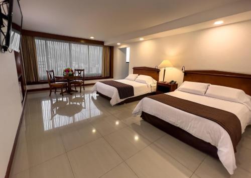 a hotel room with two beds and a table at Torre de Cali Plaza Hotel in Cali