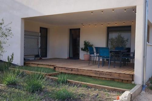 a deck with a table and chairs on it at Gîte Aux Bons Voisins in Gordes