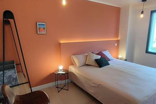 a bedroom with a large bed with an orange wall at Gîte Aux Bons Voisins in Gordes