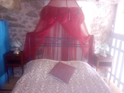 une chambre avec un lit avec des rideaux rouges et une fenêtre dans l'établissement Idéal pour les amoureux de la pierre intérieure, à Palluau