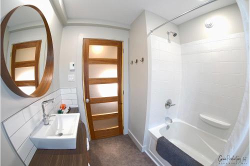 een badkamer met een wastafel, een bad en een spiegel bij Morel Executive Suites in Edmundston