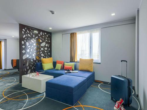 uma sala de estar com um sofá azul com almofadas coloridas em Ibis Styles Bucharest Airport em Otopeni