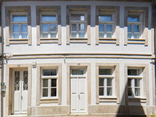 ヴィアナ・ド・カステロにあるMaria Veiga Guest Houseの白いドアと窓のある建物の外観