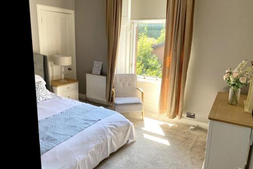 a bedroom with a bed and a window and a chair at Stunning 3 bedroom Victorian home near Pollok country park in Glasgow