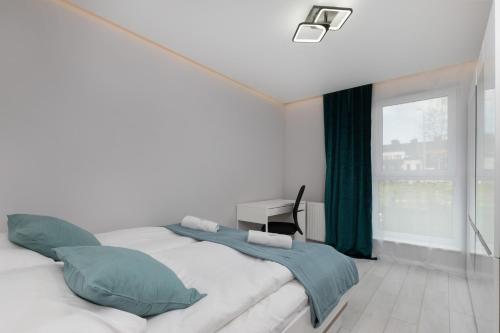 a bedroom with a large white bed with green pillows at Stunning Apartment Hokejowa with Terrace & Parking by Renters in Gdańsk