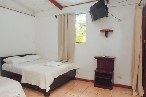a bedroom with two beds and a tv on the wall at Arrecife Punta Uva - Hospedaje, bar y restaurante - Frente al mar in Punta Uva