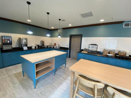 a kitchen with blue cabinets and wooden tables at Country Inn & Suites by Radisson, Champaign North, IL in Champaign