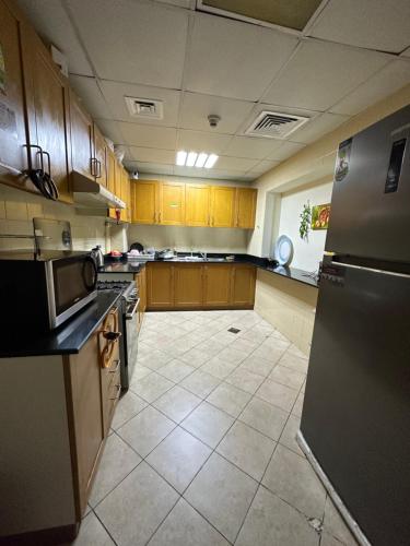 a large kitchen with wooden cabinets and a refrigerator at Partition Near Metro G-19 P02 in Dubai