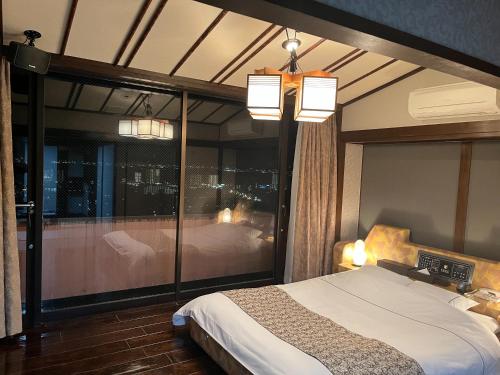 a bedroom with a bed and a large glass window at FEEL LAKE　VIEW in Otsu