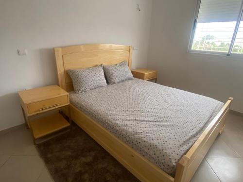 - une chambre avec un lit en bois et 2 oreillers dans l'établissement Appartement neuf meublé dans le Centre d'Agadir, à Agadir