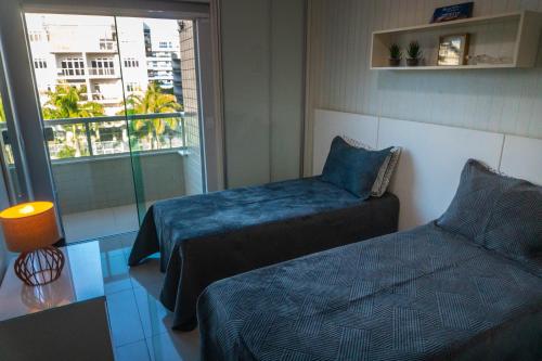 Maravilhoso Apto na Praia do Forte Wi-Fi 600 MB في كابو فريو: غرفة فندقية بسريرين ونافذة