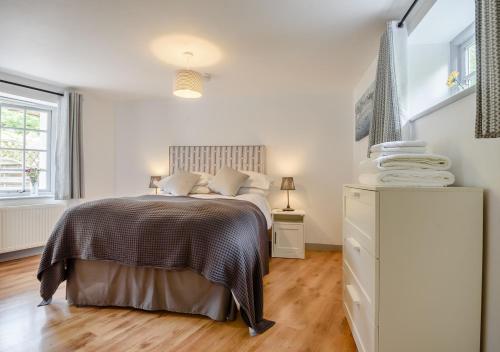 a white bedroom with a bed and a dresser at Vine Cottage in West Runton