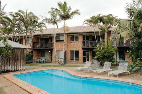 a resort with a swimming pool and palm trees at Bayside Court Apartments in Byron Bay