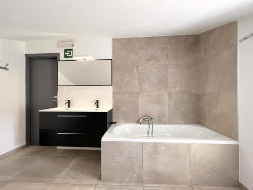 een badkamer met een bad en een wastafel bij La Ferme in Lierneux