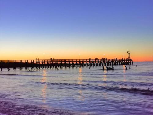 a pier in the ocean with people in the water at Charmant Duplex, 300 m de la mer in Courseulles-sur-Mer