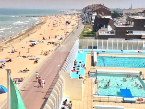 uma vista para uma praia com pessoas numa piscina em Charmant Duplex, 300 m de la mer em Courseulles-sur-Mer