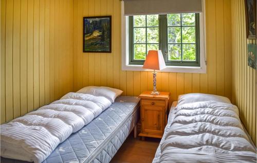 two beds in a room with a lamp and a window at Nice Home In Tuddal With Kitchen in Tuddal
