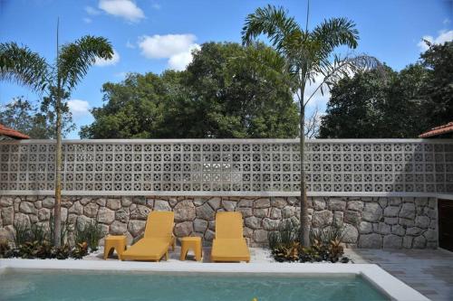 two chairs and a swimming pool next to a stone wall at Trilliza Azul in Campeche