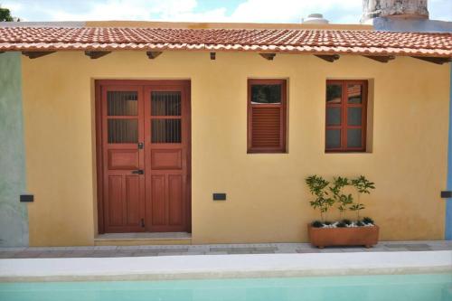 a yellow house with red doors and a potted plant at Trilliza Azul in Campeche