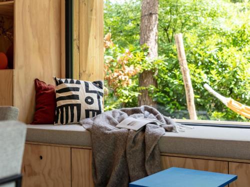 a window seat with a blanket and a book at TED Tiny House in Nunspeet