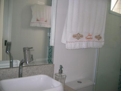 a bathroom with a sink and a toilet and towels at APTO FRENTE TOTAL P/ MAR in Guarujá