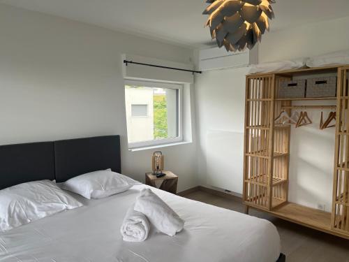 Un dormitorio con una cama con sábanas blancas y una ventana. en ENTRE NOUS CITY, en Annecy
