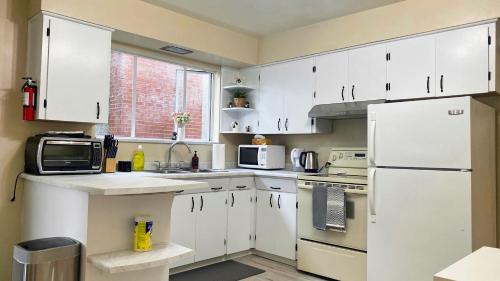 a kitchen with white cabinets and a white refrigerator at Spacious home 15mins to Downtown in Vancouver