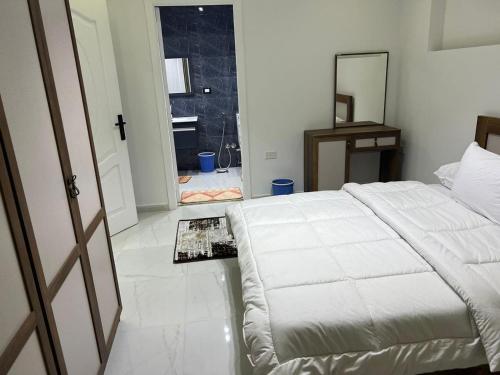 Schlafzimmer mit einem weißen Bett und einem Spiegel in der Unterkunft الفتح / المنيل / د ٤ in Kairo